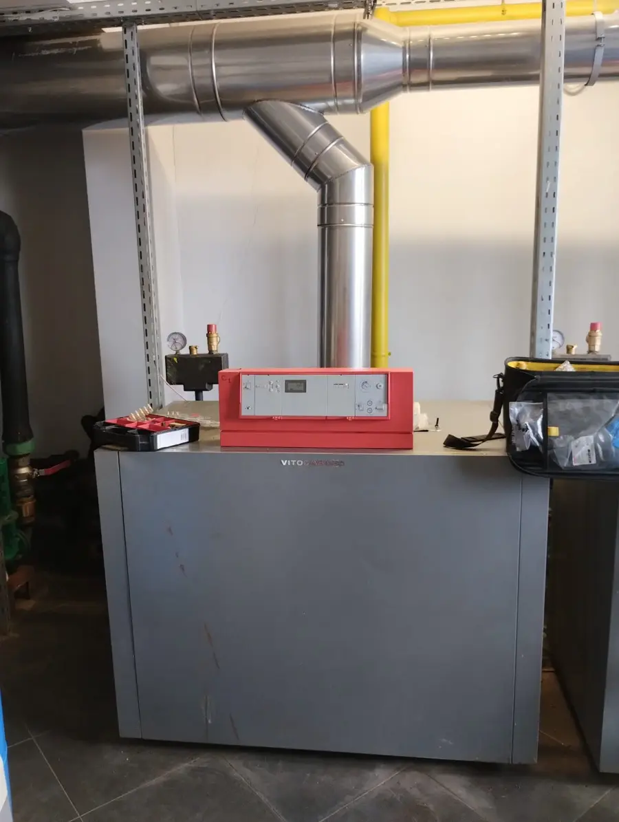 Cazan de mare putere racordat la coloana de gaz și la tubulatura de evacuare din inox, într-o sală tehnică