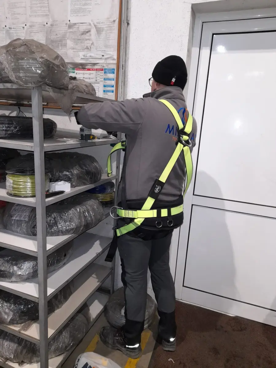 Coleg echipat cu ham de siguranță, pregătind materialele de instalații în depozit