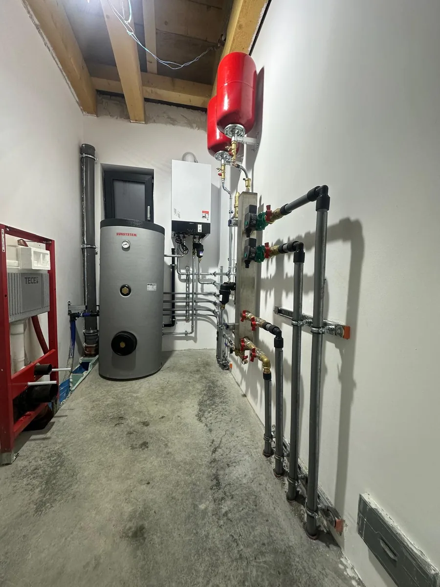 Cameră tehnică cu boiler vertical, centrală murală și traseele de distribuție pe perete